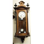 An early 20th Century walnut and part ebonised cased Vienna style wall clock with visible pendulum