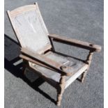 A teak framed plantation chair with rattan seat and back panel - framed cracked, holes to rattan