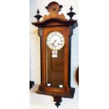 An early 20th Century walnut and part ebonised cased Vienna style wall clock with visible pendulum