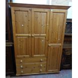 A 4' 6 1/2" modern polished pine two part wardrobe with hanging space enclosed by a pair of panelled