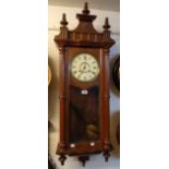 A stained walnut cased Vienna style wall clock with fret cut decoration, visible pendulum and