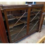 A 3' 11" 20th Century polished mahogany book cabinet in the antique style with blind fretwork frieze