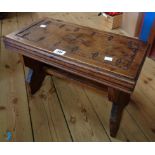 A 20" early 20th Century stained oak stool with incised decoration to oblong top, set on shaped