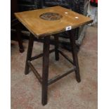 A 16" mixed wood occasional table with carved armorial decoration to square top, set on simple