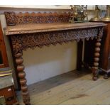 A 3' 5" late Victorian carved oak hall table with shaped raised back, set on bobbin turned front