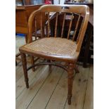 An oak framed bow chair with ring turned spindles to back and rattan seat, set on turned front