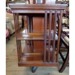A 22 3/4" Edwardian walnut revolving bookcase with moulded slatted sides, set on porcelain casters