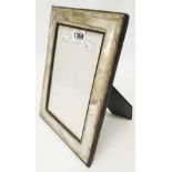 A silver fronted photograph frame with upholstered easel back - London 1985 - to take 7 1/2" X 5 1/