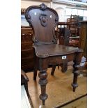 A Victorian stained oak hall chair with C-scrolls and shield panel to back set on turned front legs