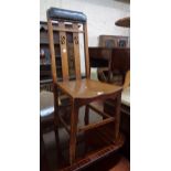 An early 20th Century stained oak framed standard chair with studded rexine top rail, pierced lath