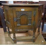 A 32" polished oak credence style cabinet enclosed by a decorative arcaded panel door, set on an