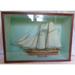A stained wood display case containing a model of the 1839 two masted top-sail clipper schooner