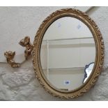 A gilt plaster framed oval wall mirror - sold with two cherubs