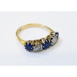 A marked 18ct. yellow metal ring, set with three sapphires interspersed with three illusion set