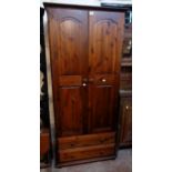 A 32" modern stained pine wardrobe with hanging space enclosed by a pair of panelled doors over