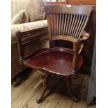 A vintage mahogany framed swivel office elbow chair set on quadruple legs with pad feet -