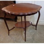 A 29" Edwardian walnut two tier occasional table with moulded oval surfaces set on slender