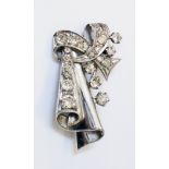 An unmarked white metal brooch of drape and scroll design, set with numerous brilliant cut diamonds