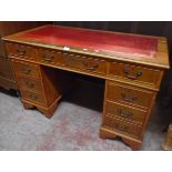 A 4' reproduction yew twin pedestal desk with red leather inset top, three frieze drawers,