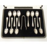 A case containing eleven matching silver teaspoons and pair of sugar tongs to match