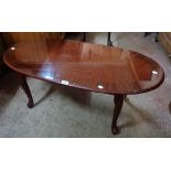 A 3' 6" reproduction quarter veneered and cross banded walnut effect oval coffee table, set on