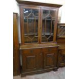 A 4' 3" early 20th Century Arts and Crafts style polished oak two part book cabinet with