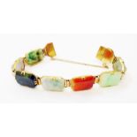 An unmarked yellow metal differing coloured jade panel bracelet with large clasp and