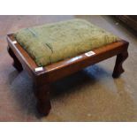 An early 20th Century stained oak framed footstool with upholstered drop-in top, set on stylised