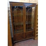 A 3' 1 1/2" early 20th Century walnut display cabinet with glass shelves enclosed by a pair of