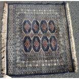 A Bokhara mat with eight medallions, gold on black main - 37" X 33" (95cm X 85cm)