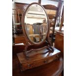 A 19th Century dressing table mirror with bevelled oval plate, set on an associated bow front base