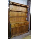 A 4' 10" modern polished pine two part dresser with two shelf open plate rack over three short