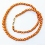 An orange coral graduated bead necklace with marked 9c rose metal clasp