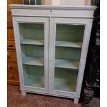 A 31 1/2" book cabinet with three shelves enclosed by a pair of glazed panel doors - later painted