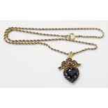 A 9ct. gold heart and bow pattern garnet set pendant, on marked 9c rope-twist neck chain