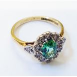 An 18ct. gold ring, set with central oval green topaz within a tiny diamond border