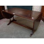 A reproduction mahogany coffee table with flanking drop-ends and slender ring turned supports