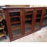 A 5' 2" Edwardian stained walnut book cabinet with shelves enclosed by three glazed panel doors, set