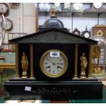 A late Victorian black slate mantle clock of architectural design with flanking figures and