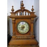 A stained oak cased mantel timepiece with ornate spindle pediment and simple American movement