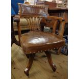 An early 20th Century swivel office bow elbow chair with studded brown leather upholstery