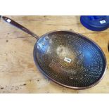 A large antique copper and iron cream strainer