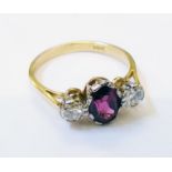 An 18ct. gold ring, set with central oval burgundy coloured ruby with flanking diamonds