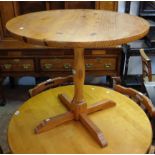 A 34" diameter modern polished pine pedestal dining table - sold with a set of four spindle back