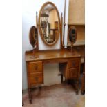 A 3' 3" early 20th Century walnut kneehole dressing table with central bevelled oval mirror and