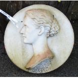 A white marble high relief profile portrait bust, set on an 18" diameter wall plaque