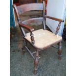 An antique stained elm Windsor elbow commode chair with converted seat panel, set on ring turned