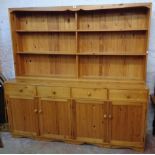 A 6' 5" 20th Century polished pine two part dresser with segmented three shelf plate rack to top,