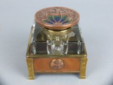 AN ARTS & CRAFTS STYLE SQUARE GLASS INKWELL, hinged circular copper cover with cast foliate motif