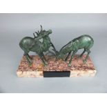 AN ART DECO STYLE FIGURE GROUP OF TWO VERDIGRIS BRONZED SPELTER RUTTING STAGS, mounted on a